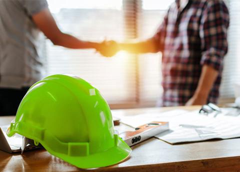 Green hard hat and hand shake